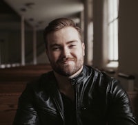 a man in a leather jacket sitting in a church pew